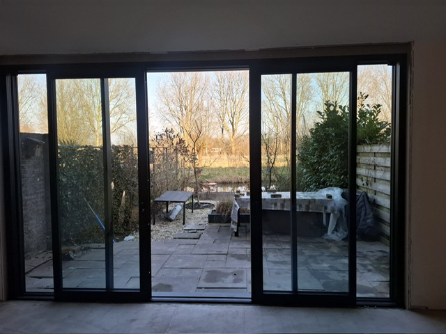 Moderne aluminium schuifpui in een woonkamer met uitzicht op de tuin